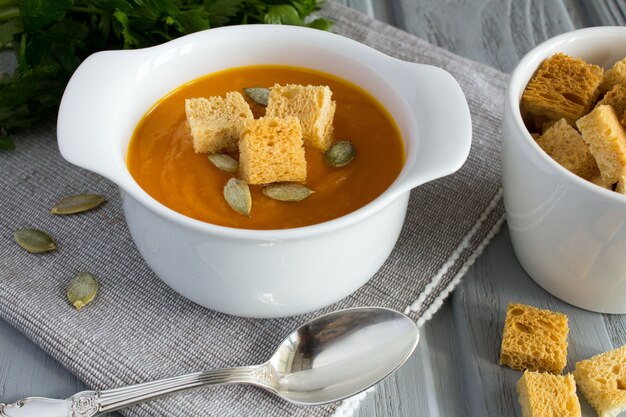 Sopa de calabaza y bizcochos en el fondo de madera gris