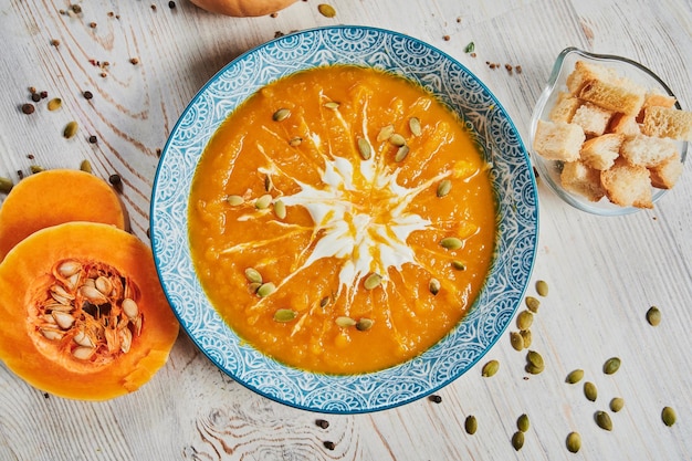 Sopa de calabaza en un bol con calabazas frescas ajo y hierbas de perejil