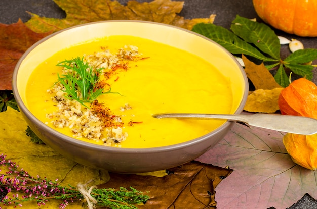 Sopa de calabaza caliente con hojas secas de otoño.