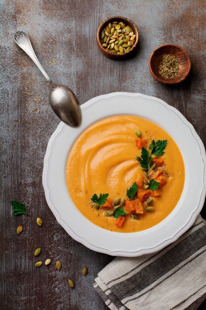 Sopa de calabaza casera en plato de cerámica blanca sobre un antiguo hormigón o piedra