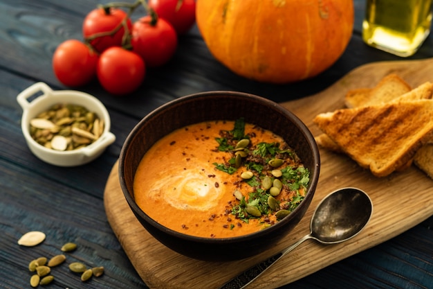 Sopa de calabaza con crema agria y semillas de calabaza en una mesa de madera.