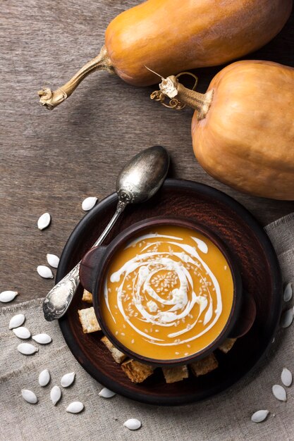 Foto sopa de calabaza con crema y semillas de sésamo con crutones en madera