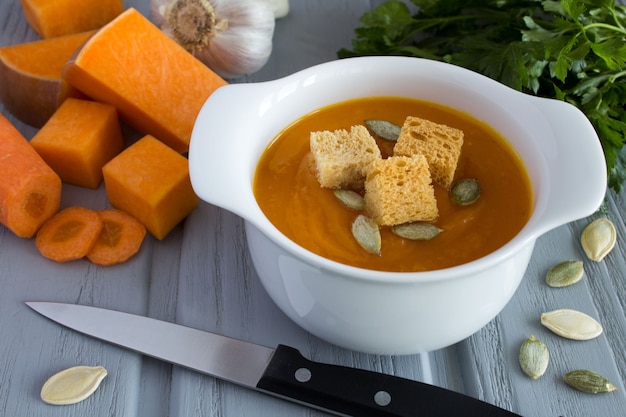 Sopa con calabaza e ingredientes en el fondo de madera gris