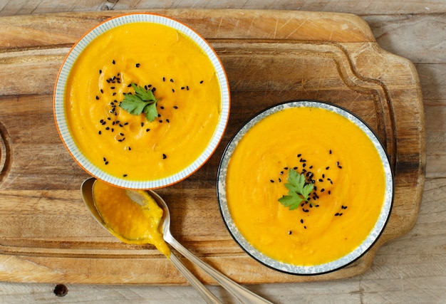 Sopa de calabaza fresca en los tazones sobre una mesa de madera