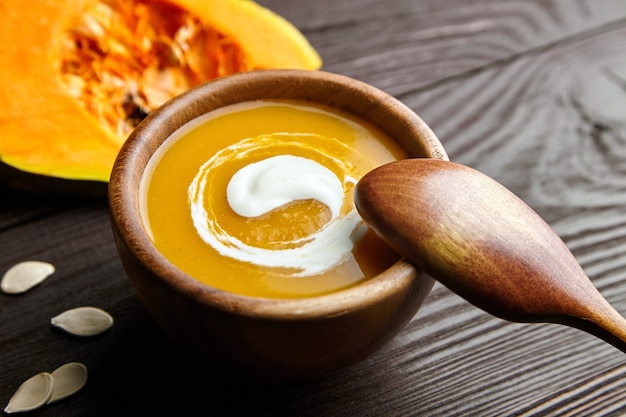 Sopa de calabaza de otoño vegetariana con crema agria en un tazón de madera con cuchara
