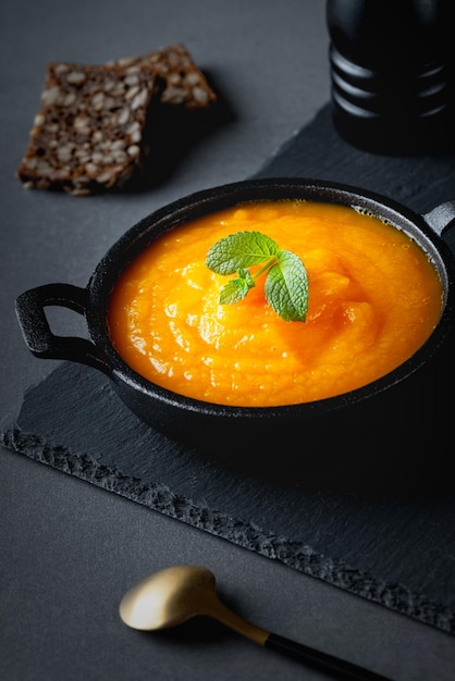 Sopa de calabaza y pan de centeno en mesa gris