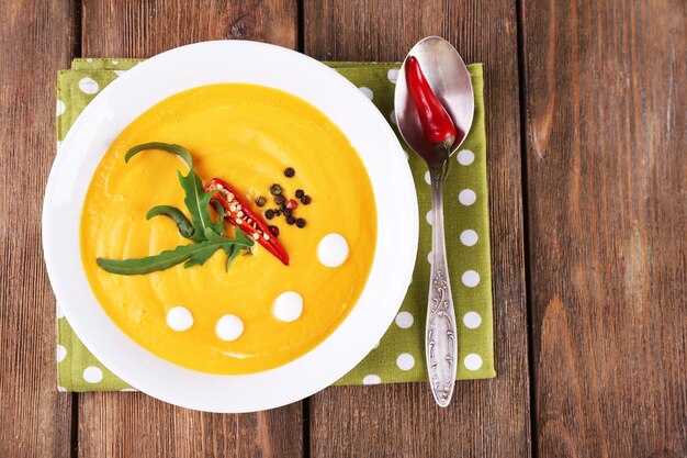 Sopa de calabaza en plato blanco sobre servilleta sobre fondo de madera