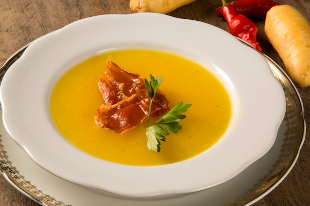 Sopa de calabaza con prosciutto en mesa