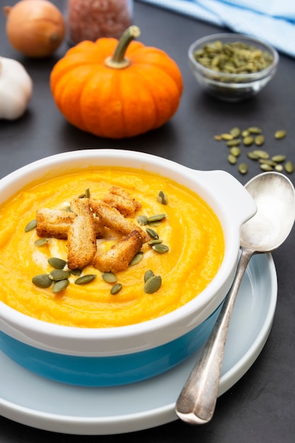 Sopa de calabaza en un recipiente con semillas de calabaza frescas. Alimentos de otoño