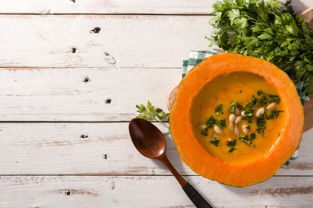 Sopa de calabaza y zanahoria en mesa de madera blanca.