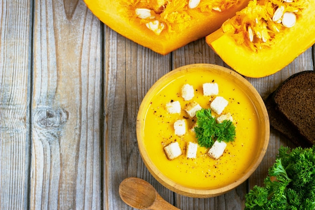 Foto sopa de calabaza y zanahoria, tadka con crema y perejil en mesa de madera oscura. vista superior.