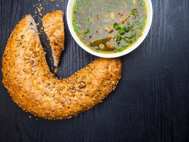 Sopa caliente de acedera y espinacas con pan bagel sobre fondo de madera