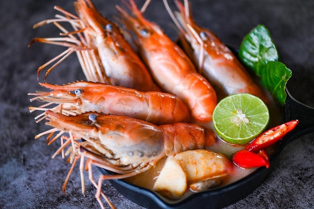 Sopa de camarones en un tazón de sopa de mariscos con hierbas y especias tailandesas Comida tailandesa Tom Yum Kung Camarones picantes agridulces sopa de gambas al curry lima limón galanga chile rojo champiñones de paja en la comida de mesa