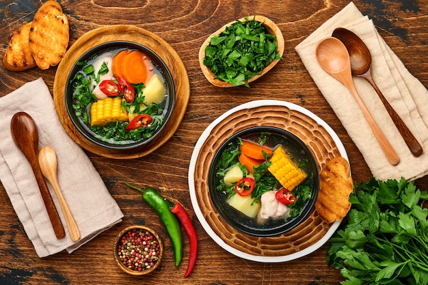 Sopa de carne chilena con pampkin, maíz, cilantro fresco y patatas sobre fondo de mesa de madera vieja. Cazuela. Comida latinoamericana.