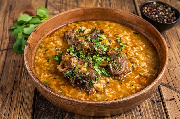 Sopa de carne de cordero Kharcho georgiano con arroz, tomates y especias en un cuenco de madera. de madera