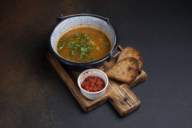 Foto sopa con carne y verduras en una olla sobre un fondo oscuro