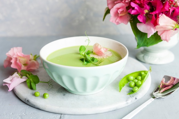 Sopa caseira de creme de ervilha verde fresca com brotos de ervilha e flores