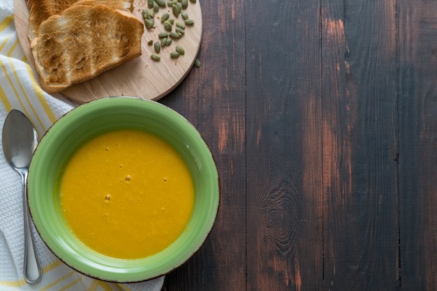 Sopa caseiro de creme de abóbora vegetariana com sementes e pão, vista superior.