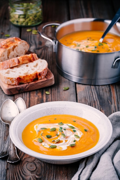 Sopa casera de calabaza con crema y semillas sobre fondo de madera