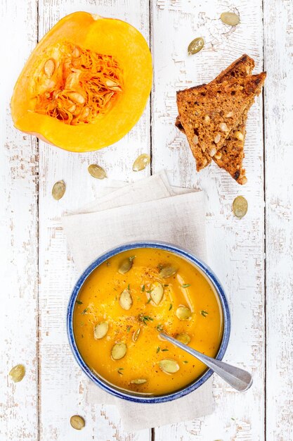 Sopa casera de crema de calabaza con semillas y vista superior de pan tostado