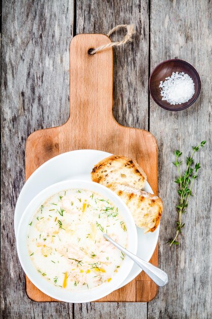 Sopa casera con salmón y crema sobre fondo de madera con picatostes