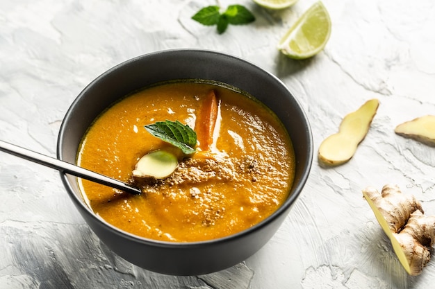 Sopa casera de zanahoria con pimientos al horno y queso jugo de lima y jengibre servida con nueces y menta fresca