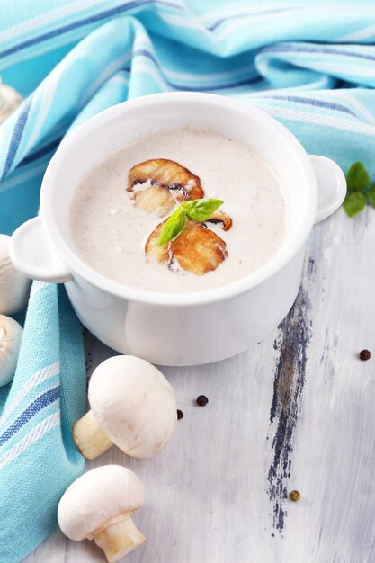 Sopa de champiñones en una olla blanca sobre una servilleta sobre fondo de madera