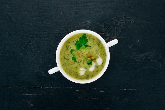 Foto sopa com brócolis e ervilhas e legumes em uma tigela comida saudável em um fundo preto de madeira vista superior copie o espaço para o seu texto