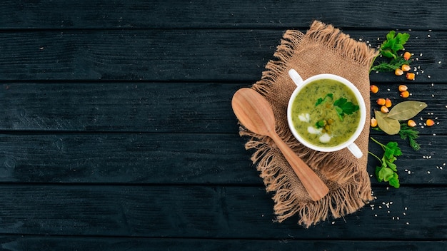 Sopa com brócolis e ervilhas e legumes em uma tigela comida saudável em um fundo preto de madeira vista superior copie o espaço para o seu texto