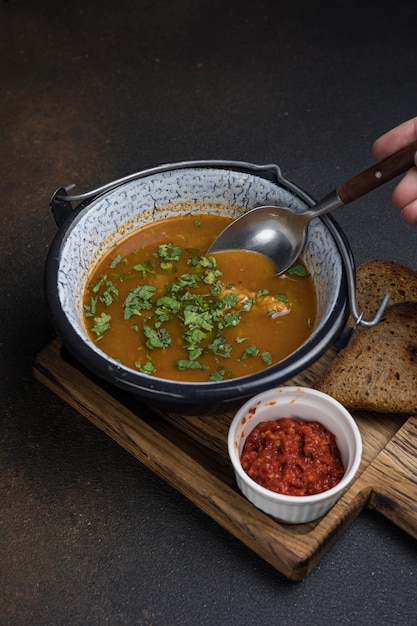 Foto sopa com carne e legumes em uma panela sobre um fundo escuro