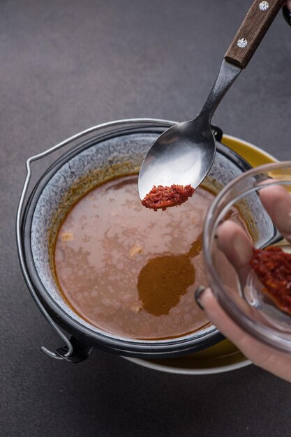 Foto sopa com carne e legumes em uma panela sobre um fundo escuro