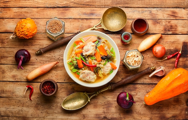 Sopa com frango, abóbora e brócolis na velha mesa de madeira rústica