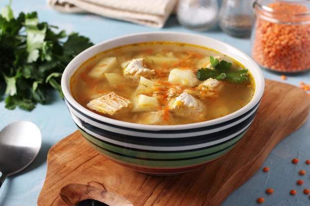 Sopa com legumes de peru e lentilhas vermelhas na tigela sobre uma tábua de madeira fechada