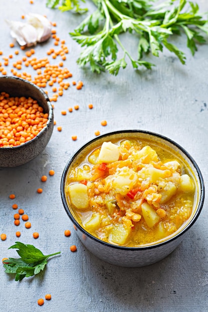 Sopa com lentilhas vermelhas e legumes em uma tigela sobre fundo azul Prato tradicional turco