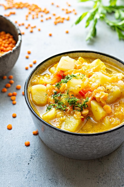 Sopa com lentilhas vermelhas e legumes em uma tigela sobre fundo azul Prato tradicional turco