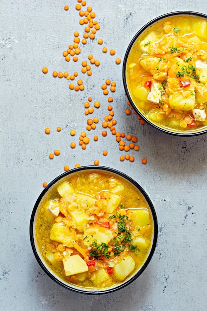 Sopa com lentilhas vermelhas e legumes em uma tigela sobre fundo azul Prato tradicional turco