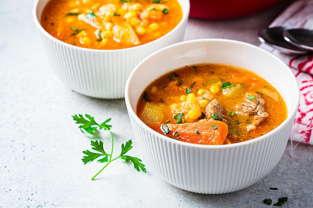 Sopa cozida lentamente de carne de bovino com milho de batata de cenoura e batata-doce Conceito de comida de conforto de inverno