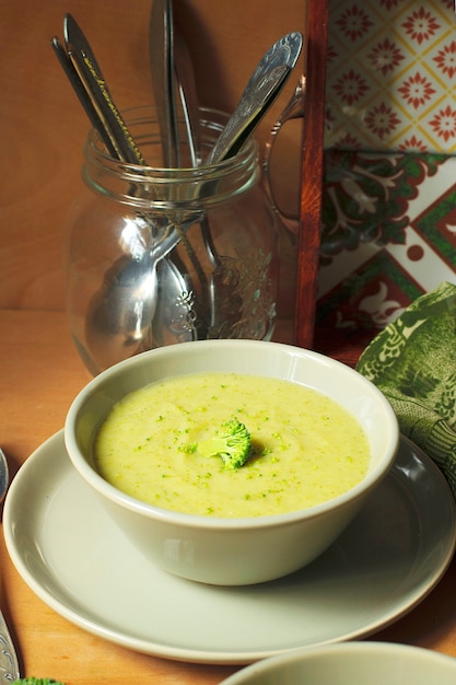 Sopa de crema de brócoli fresco en dos cuenco de cerámica gris en un plato con una cuchara sobre fondo de mármol.