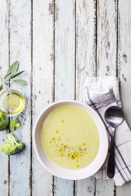 Sopa de crema de brócoli en un tazón blanco sobre fondo de madera vista superior