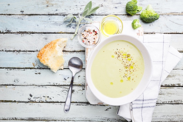 Sopa de crema de brócoli en un tazón blanco sobre fondo de madera vista superior