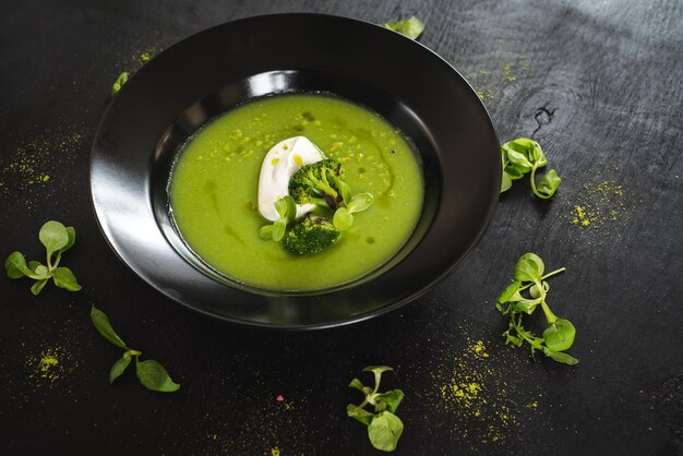 Sopa de crema de brócoli verde sobre negro