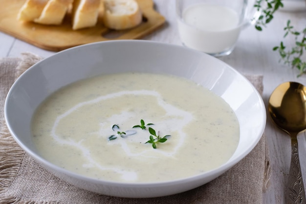 Sopa crema de calabacín y patatas sobre mesa de madera con tomillo