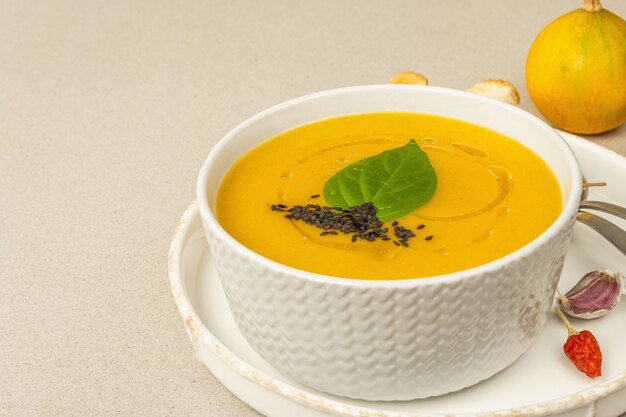 Sopa de crema de calabaza. Comida tradicional de otoño. Plato caliente, verduras maduras, especias aromáticas. Fondo de hormigón de piedra clara, espacio de copia