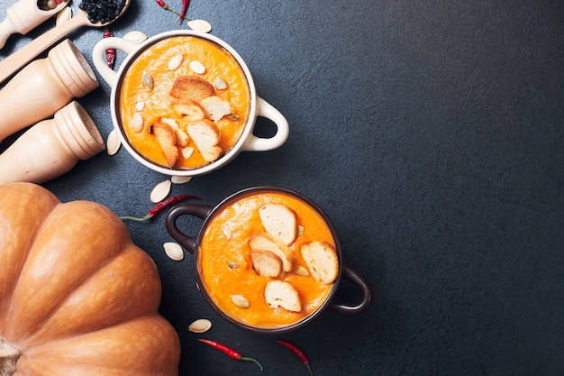 Sopa de crema de calabaza con picatostes sobre una mesa negra con especias. Foto de alta calidad