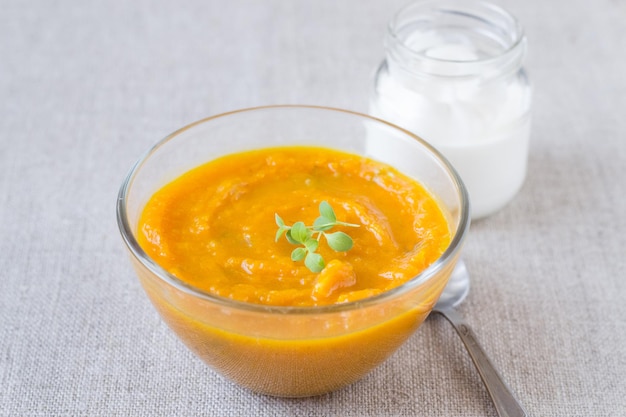 Sopa de crema de calabaza en un recipiente de vidrio y crema agria