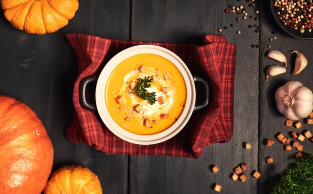 Sopa de crema de calabaza servida con crutones, nueces trituradas y perejil