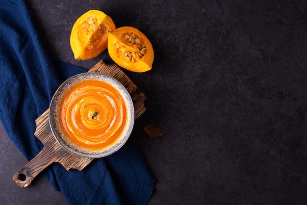 Sopa de crema de calabaza vegetal en un recipiente sobre una mesa oscura.