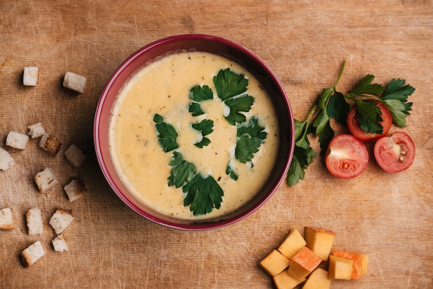 Sopa de crema de calabaza y verduras en un plato sobre una tabla de cortar con perejil