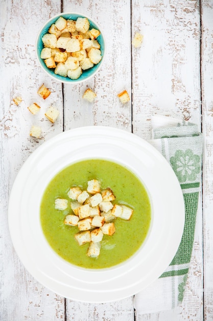 Sopa de crema casera con brócoli y picatostes sobre fondo de madera