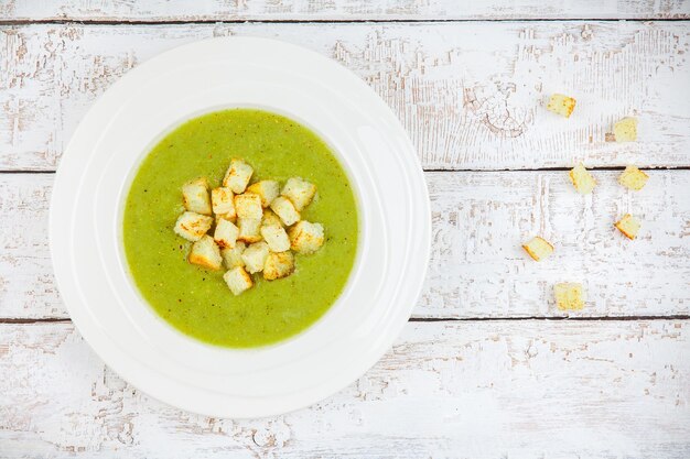 Sopa de crema casera con brócoli y picatostes sobre fondo de madera